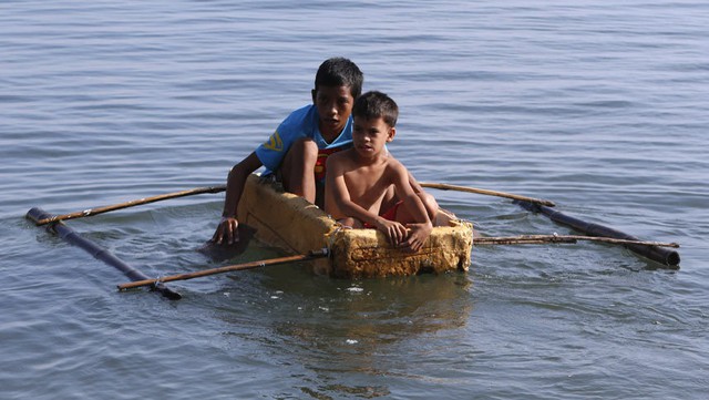 Hai cậu bé chèo thuyền làm từ xốp tủ lạnh tại ngôi làng ven biển ở thành phố Tacloban, Philippines. Đây là thành phố bị tàn phá nặng nề bởi siêu bão Haiyen vào năm ngoái.