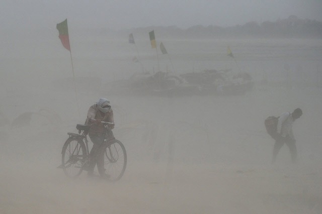 Người dân đi trong bão cát dọc bờ sông Hằng ở Allahabad, Ấn Độ.
