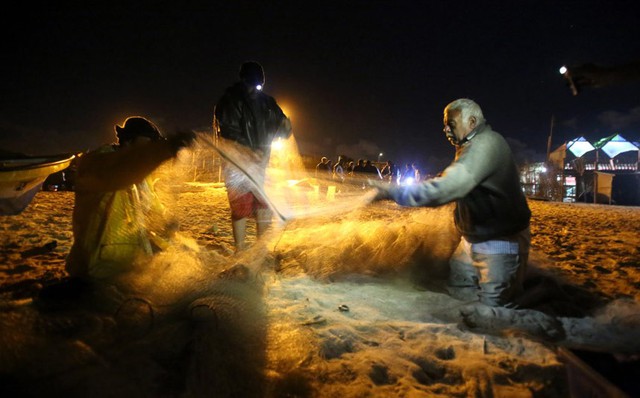 Các ngư dân Palestine kiểm tra lưới đánh cá trên bãi biển ở thành phố Gaza.