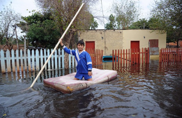 Một cậu bé di chuyển bằng chiếc đệm trên đường phố ngập lụt ở Asuncion, Paraguay.
