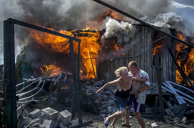 Người dân chạy khỏi các ngôi nhà bị cháy sau cuộc không kích của quân đội chính phủ nhằm vào thành phố Luganskaya, miền đông Ukraine.