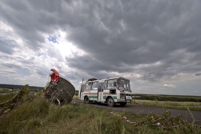 Một xe bus chạy qua một mảnh của thân máy bay MH17 bị bắn rơi gần ngôi làng Hrabove, miền đông Ukraine.