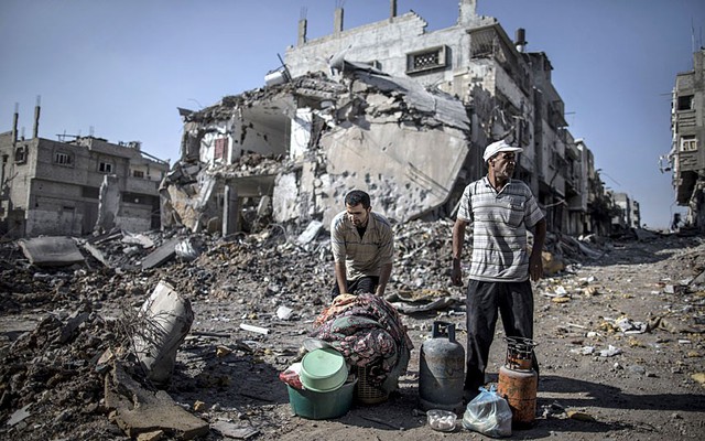 Những người đàn ông Palestine thu lượm những thứ họ tìm được từ các tòa nhà bị phá hủy trong cuộc không kích của quân đội Israel vào quận Shejaiya, thành phố Gaza.
