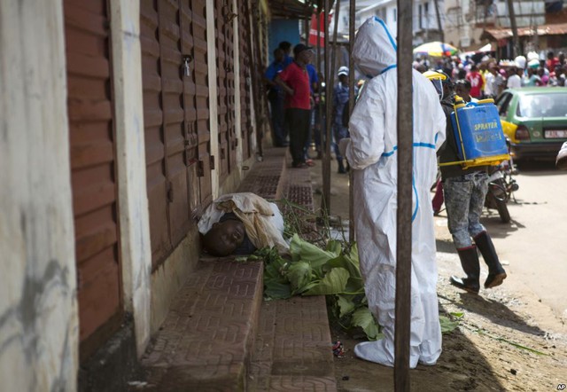 Nhân viên y tế lấy mẫu từ thi thể của một người bị nghi tử vong do nhiễm virus Ebola trên đường phố ở Freetown, Sierra Leone.