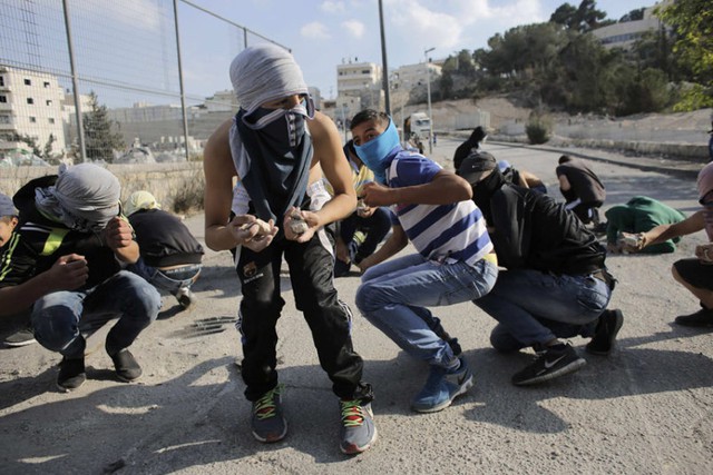 Người biểu tình Palestine cầm đá, bịt mặt trong khi đụng độ với cảnh sát Israel tại khu định cư của người Do Thái Issawiya ở Jerusalem.