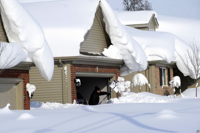 Người đàn ông đang dọn tuyết trên lối đi vào nhà mình ở Lancaster, New York, Mỹ.