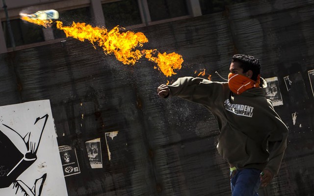 Một người biểu tình chống chính phủ ném bom xăng vào cảnh sát trên đường phố ở Caracas, Venezuela.