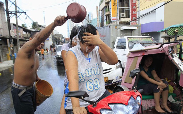 Một người đàn ông đổ nước lên đầu những người đi xe máy để mừng ngày lễ St. John tại thành phố San Juan, Philippines.