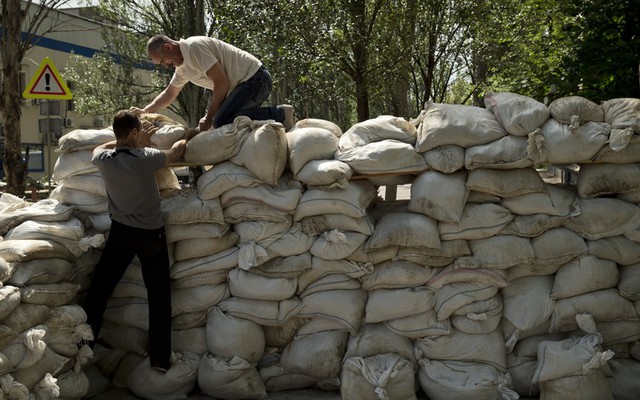 Mọi người xếp bao tải cát để lập trạm kiểm soát trên đường tới sân bay ở vùng Donetsk, Ukraine.