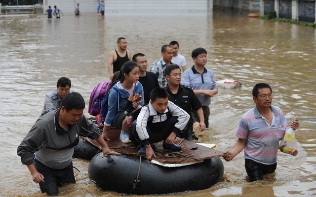 Mọi người đưa học sinh khỏi trường tiểu học ngập lụt ở huyện Bình Bá, tỉnh An Huy, Trung Quốc.