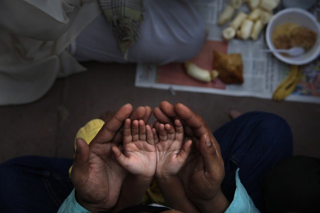 Một người đàn ông theo đạo Hồi đỡ tay con gái nhỏ trong khi cầu nguyện trong dịp tháng lễ Ramadan tại nhà thờ Jama ở New Delhi, Ấn Độ.