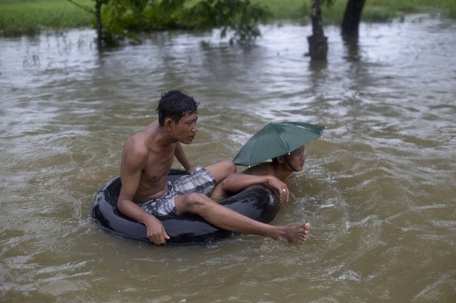 Những người đàn ông di chuyển trên đường ngập trong nước lũ ở Myanmar.