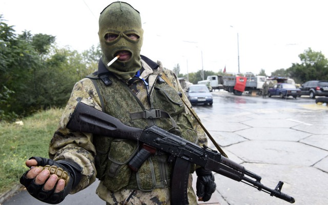 Tay súng ly khai thân Nga cầm lựu đạn trong khi đứng bảo vệ một trạm kiểm soát trên đường tới sân bay Donetsk, miền đông Ukraine.