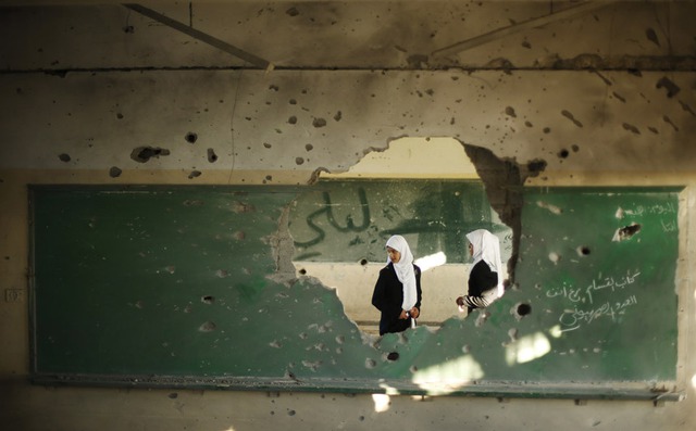 Các học sinh người Palestine nhìn vào trong một lớp học, bị trúng đạn pháo trong một đợt tấn công của quân đội Israel nhằm vào thành phố Gaza.