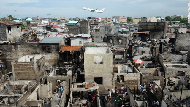 Phi cơ của hãng hàng không Japan Airlines bay qua những ngôi nhà bị cháy ở Manila, Philippines.