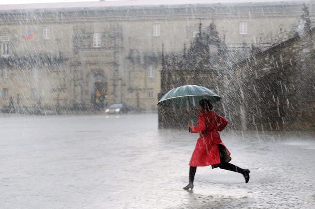 Một phụ nữ chạy dưới trời mưa lớn trên quảng trường Obradoiro ở Santiago de Compostela, Galicia, Tây Ban Nha.