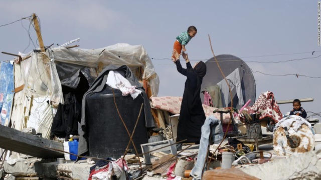 Người phụ nữ Palestine chơi với con trên đống đổ nát ngôi nhà của họ tại thành phố Khuzaa, Dải Gaza.