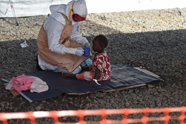 Nhân viên y tế co một em bé nhiễm virus Ebola uống thuốc tại trung tâm điều trị Kenama ở Sierra Leone.