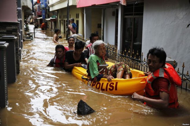 Nhân viên cứu hộ dùng thuyền để sơ tán cụ bà khỏi khu vực ngập lụt ở quận Jatinegara, Jakarta, Indonesia.