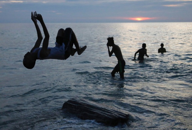 Thanh niên chơi dưới hoàng hôn trên bãi biển Cora Eva ở Dobo, quần đảo Aru, Indonesia.