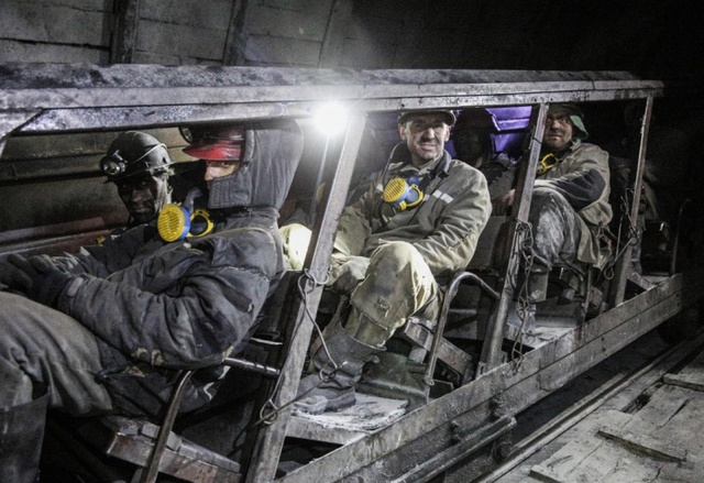 Công nhân mỏ ngồi trên xe goòng dưới mỏ than Kirov ở vùng Donetsk, miền đông Ukraine.