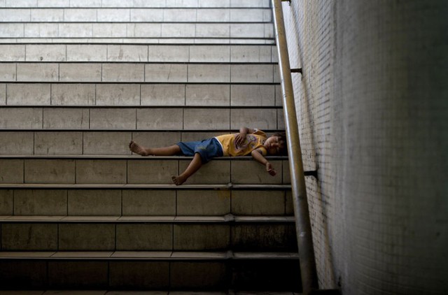 Một em bé ngủ trên bậc thang dưới đường hầm dành cho người đi bộ ở Manila, Philippines.
