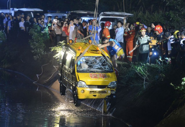 Các nhân viên cứu hộ vớt một chiếc xe bus sau khi nó lao xuống ao tại thành phố Tương Đàm, Trung Quốc, khiến 11 người, bao gồm 8 trẻ em thiệt mạng.