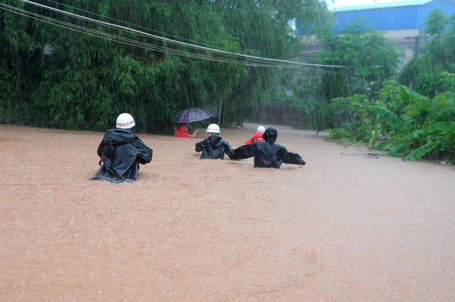 Nhân viên cứu hộ tìm kiếm các nạn nhân mắc kẹt trên đường phố ngập lụt ở thành phố Khâm Châu, Trung Quốc.