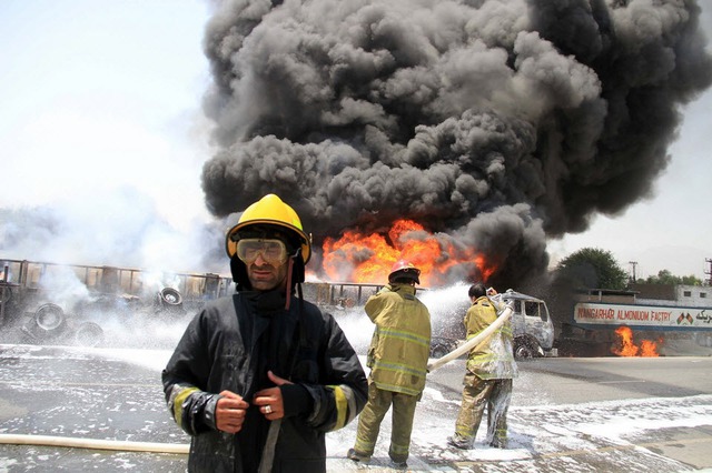 Lính cứu hỏa cố gắng dập tắt các xe chở dầu của NATO bốc cháy sau khi bị phiến quân tấn công ở Nangarhar, Afghanistan.