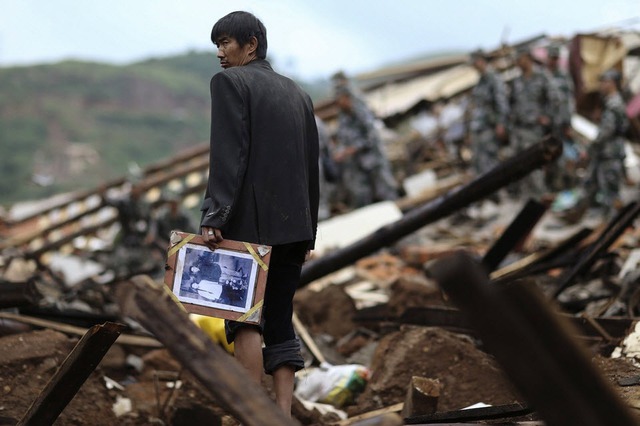Người đàn ông đứng giữa đống đổ nát của các ngôi nhà sau trận động đất ở thị trấn Ludian, tỉnh Vân Nam, Trung Quốc.