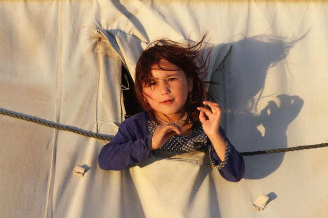 Bé gái chụp ảnh tại một túp lều tạm trong trại tị nạn ở ngoại ô thành phố Herat, Afghanistan.