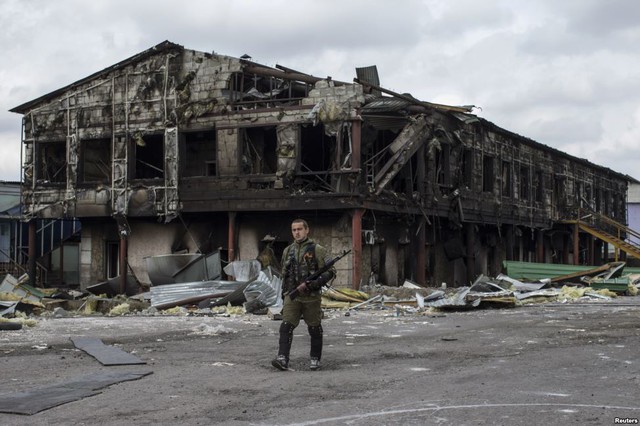 Tay súng ly khai thân Nga đi trước một nhà máy bị phá hủy trong cuộc nã pháo gần đây tại thị trấn Nizhnaya Krinka, miền đông Ukraine.