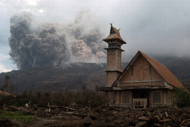 Núi lửa Sinabung tiếp tục phun trào tro bụi sau nhà thờ bỏ hoang trên đảo Sumatra, Indonesia.