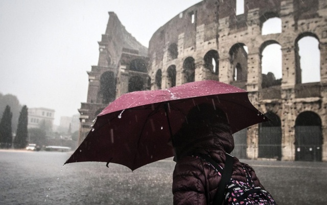 Cô gái đi dưới trời mưa lớn gần Đấu trường cổ La mã ở thủ đô Rome, Italia.