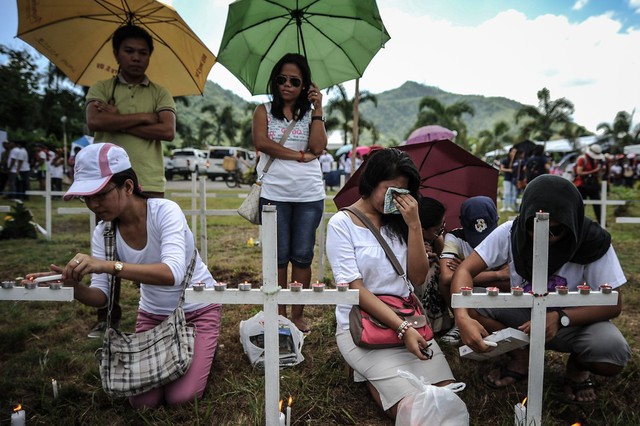 Thành viên gia đình thăm mộ của các nạn nhân thiệt mạng trong trận siêu bão Haiyen cách đây 1 năm, tại khu mộ tập thể ở ngoại ô thành phố Tacloban, Philippines.