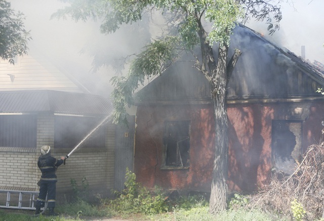 Lính cứu hỏa cố gắng dập tắt một ngôi nhà cháy sau khi bị trúng đạn pháo của đội chính phủ tại thành phố Luhansk, Ukraine.