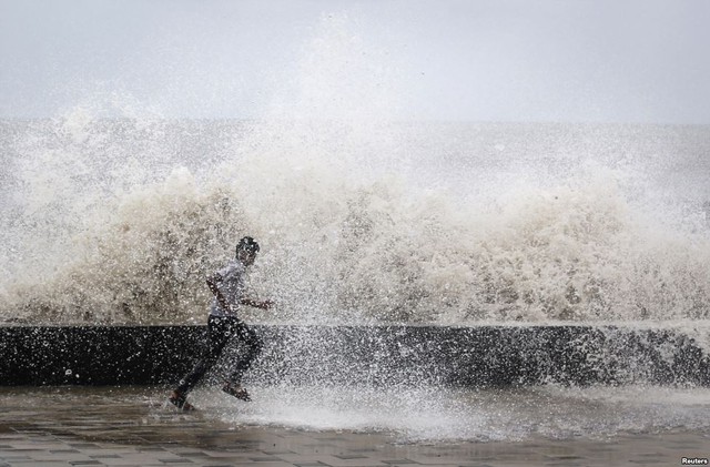 Cậu bé chạy trên bờ biển khi một đợt sóng lớn ập vào bờ tại thành phố Mumbai, Ấn Độ.
