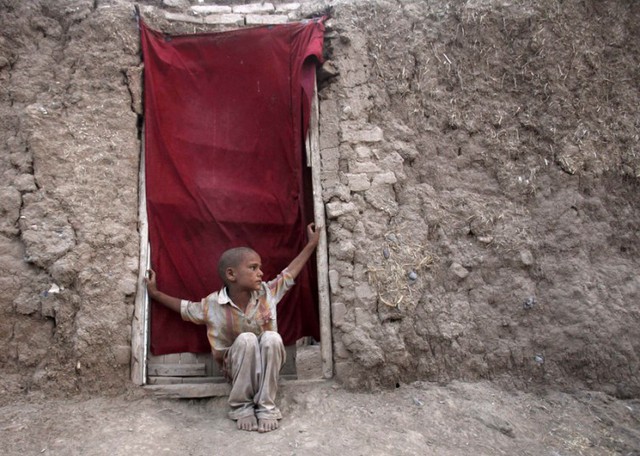 Một bé tị nạn người Afghanistan ngồi trước cửa nhà tại ngôi làng Sardaryab ở ngoại ô Peshawar, Pakistan.