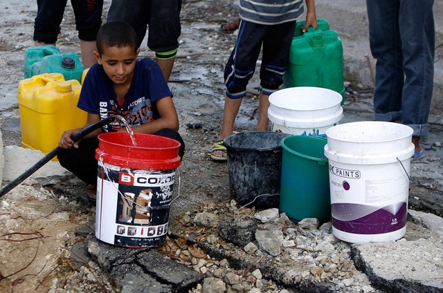 Trẻ em Palestine lấy nước từ một đường ống nước vỡ tại quân al-Shejaea, thành phố Gaza.