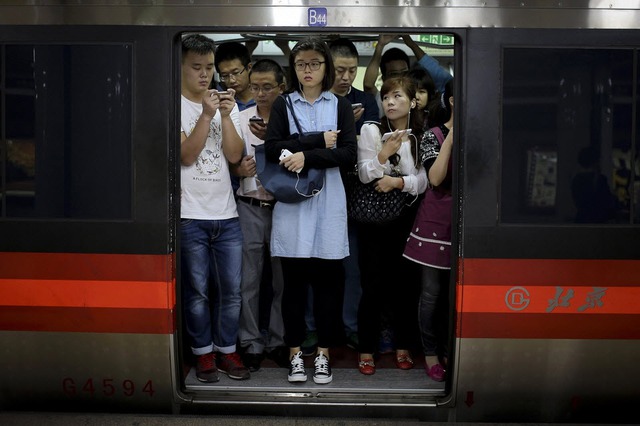 Hành khách dán mắt vào điện thoại trên một chuyến tàu điện ngầm đông đúc vào giờ cao điểm ở Bắc Kinh, Trung Quốc.