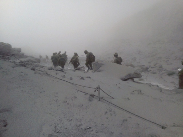 Các nhân viên cứu hộ thuộc Lực lượng phòng vệ Nhật Bản đi xuống sườn dốc phủ đầy tro bụi phun trào từ núi lửa Ontake.