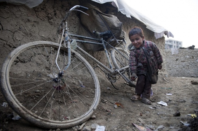 Cậu bé chơi với xe đạp tại một trại tị nạn dành cho những người mất nhà cửa ở Kabul, Afghanistan.
