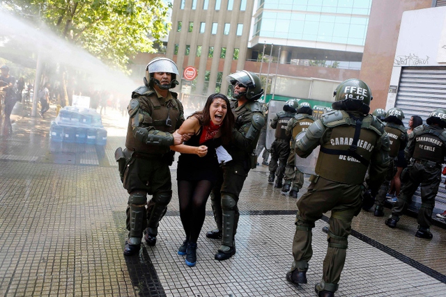 Cảnh sát chống bạo động bắt giữ một sinh viên biểu tình ở Santiago, Chile.