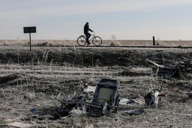 Người đàn ông đạp xe qua xác máy bay MH17 của hãng hàng không Malaysia Airlines gần ngôi làng Hrabove, Donetsk, miền đông Ukraine.