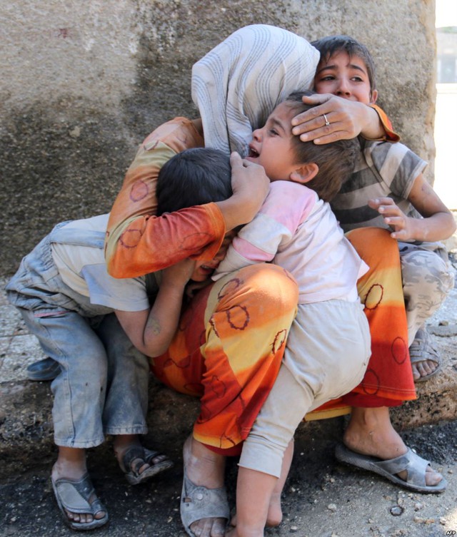 Người mẹ cố gắng trấn an những đứa con sau khi nhà họ bị đánh bom ở thành phố Aleppo, Syria.