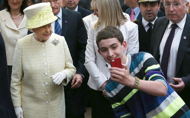 Một cậu bé chụp ảnh “tự sướng” trước Nữ hoàng Anh, khi bà tới thăm khu chợ trong nhà tại Belfast, Bắc Ireland.