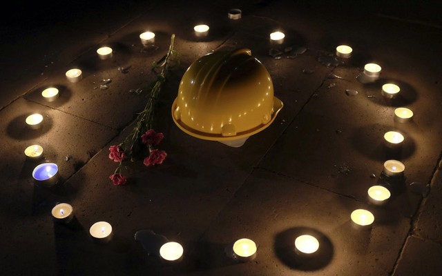 Mũ của thợ mỏ và hoa được người biểu tình đặt giữa những cây nến để cầu nguyện cho các nạn nhân thiệt mạng trong vụ nổ mỏ than ở Soma, Thổ Nhĩ Kỳ.