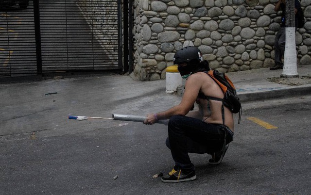 Một người biểu tình phóng pháo tự chế nhằm vào cảnh sát chống bạo động ở Caracas, Venezuela.