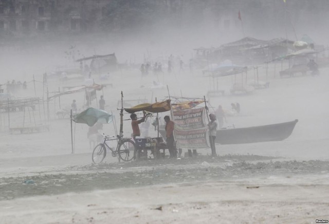 Người đàn ông buộc lại tấm bạt che tại cửa hàng của mình trong bão cát trên bờ sông Hằng ở thành phố Allahabad, Ấn Độ.