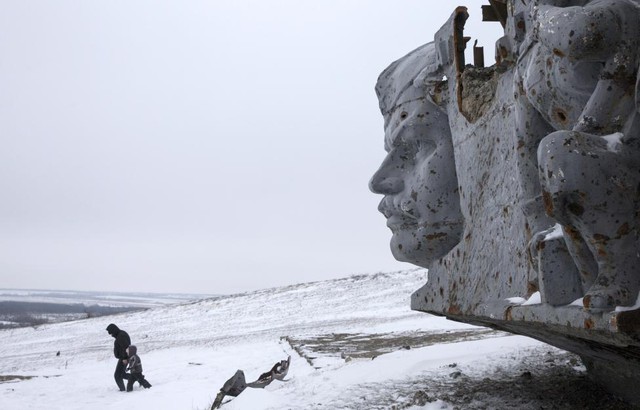 Người đàn ông dắt con trai đi trên tuyết gần tượng đài chiến tranh bị phá hủy ở Savur-Mohyla, gần thành phố Donetsk, miền đông Ukraine.
